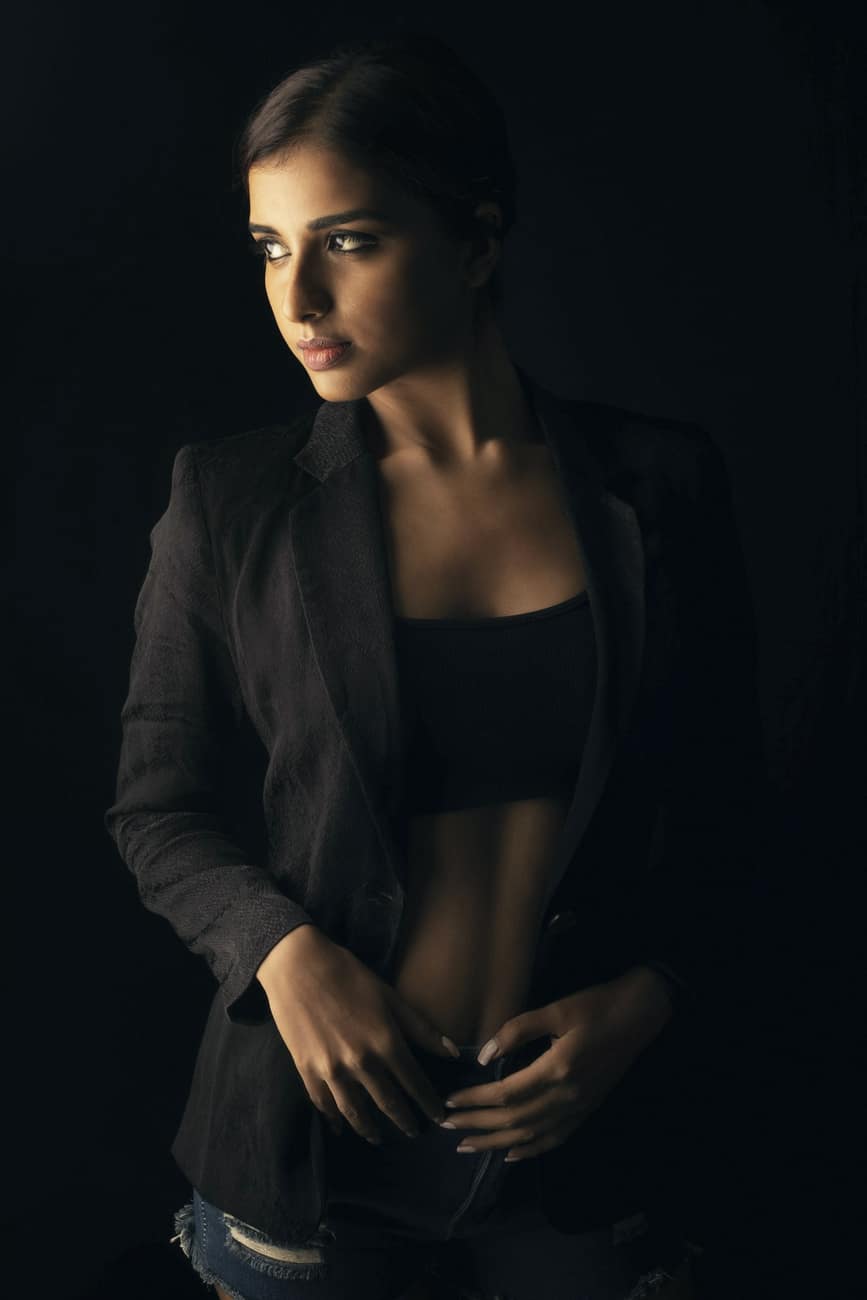 Mulher com blazer escuro aberto sobre top preto em luz baixa