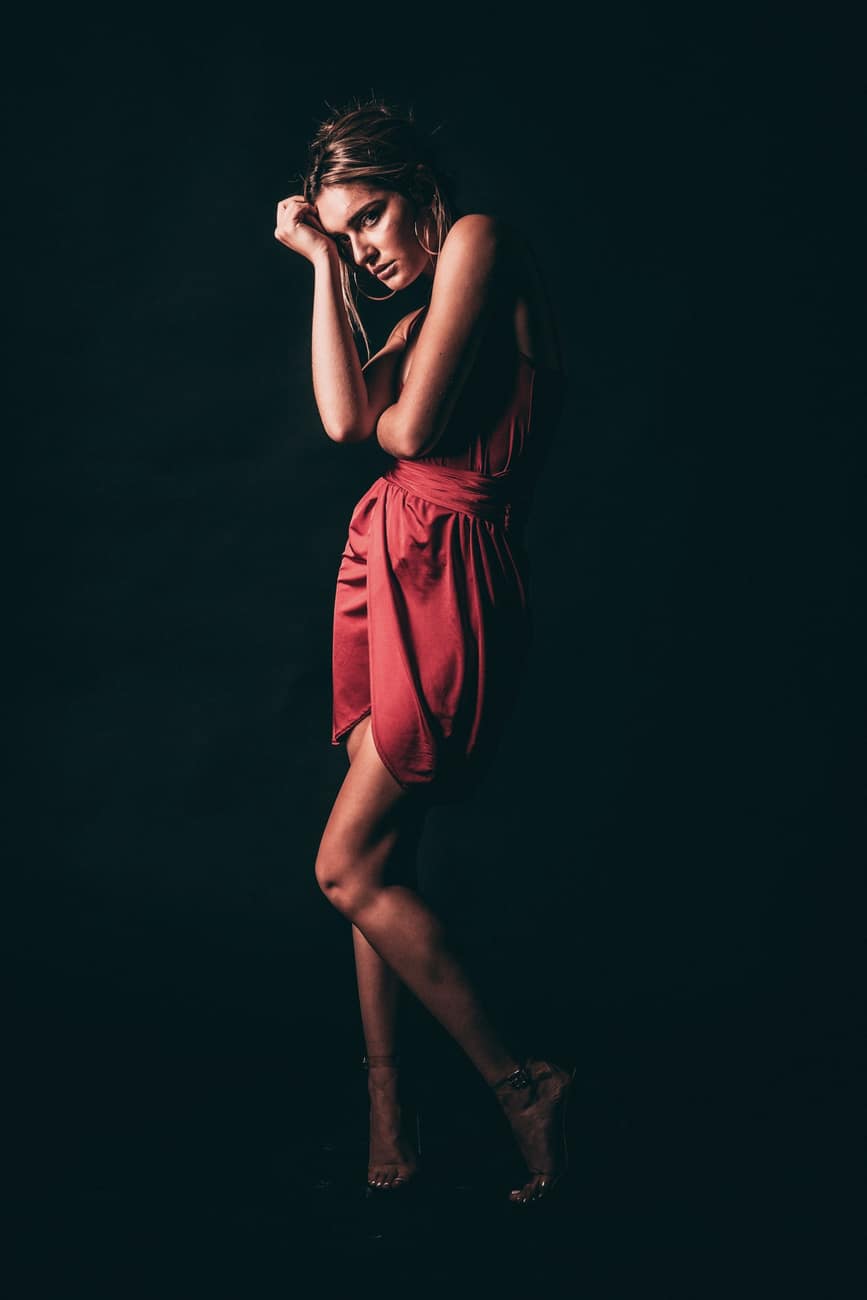 Mulher de vestido vermelho de cetim em estúdio escuro