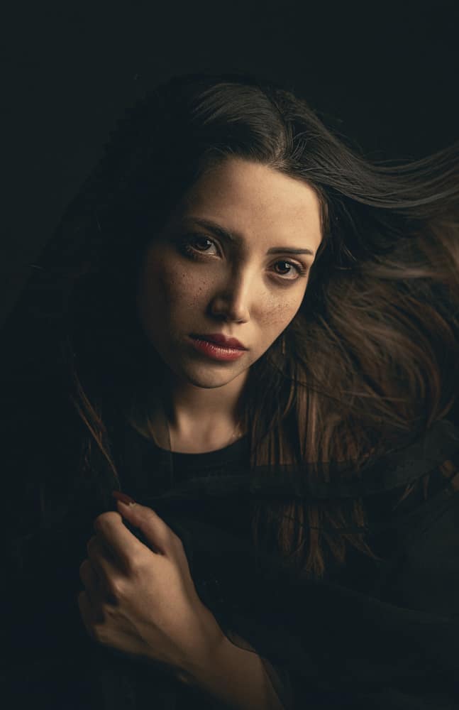 Retrato de Lia Fontes, mulher de cabelo longo castanho, em luz quente