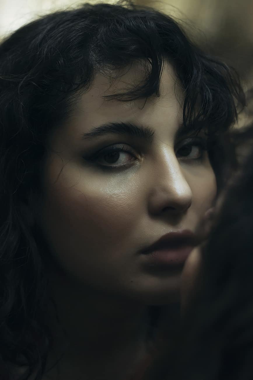 Close-up de modelo de cabelo cacheado escuro em luz quente e baixa