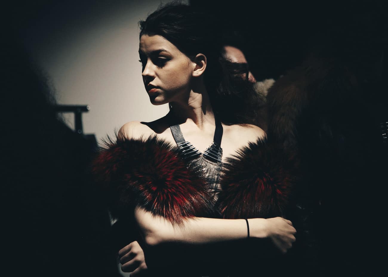 Bastidor de desfile: stylist ajusta a estola de pelo da modelo antes de entrar
